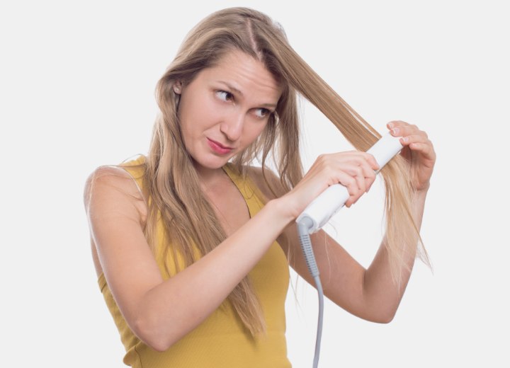 Mulher que está usando um alisador de cabelo